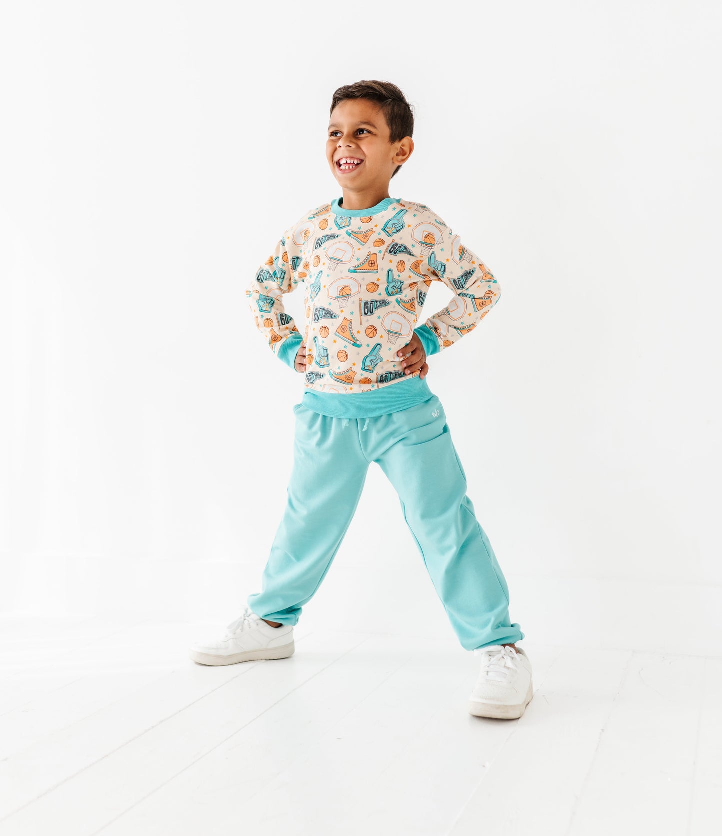Child wearing a sports themed bamboo shirt and light blue pants on a white background