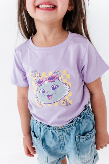 Child wearing a purple 44 Cats bamboo blend t-shirt with a cartoon cat design on a white background
