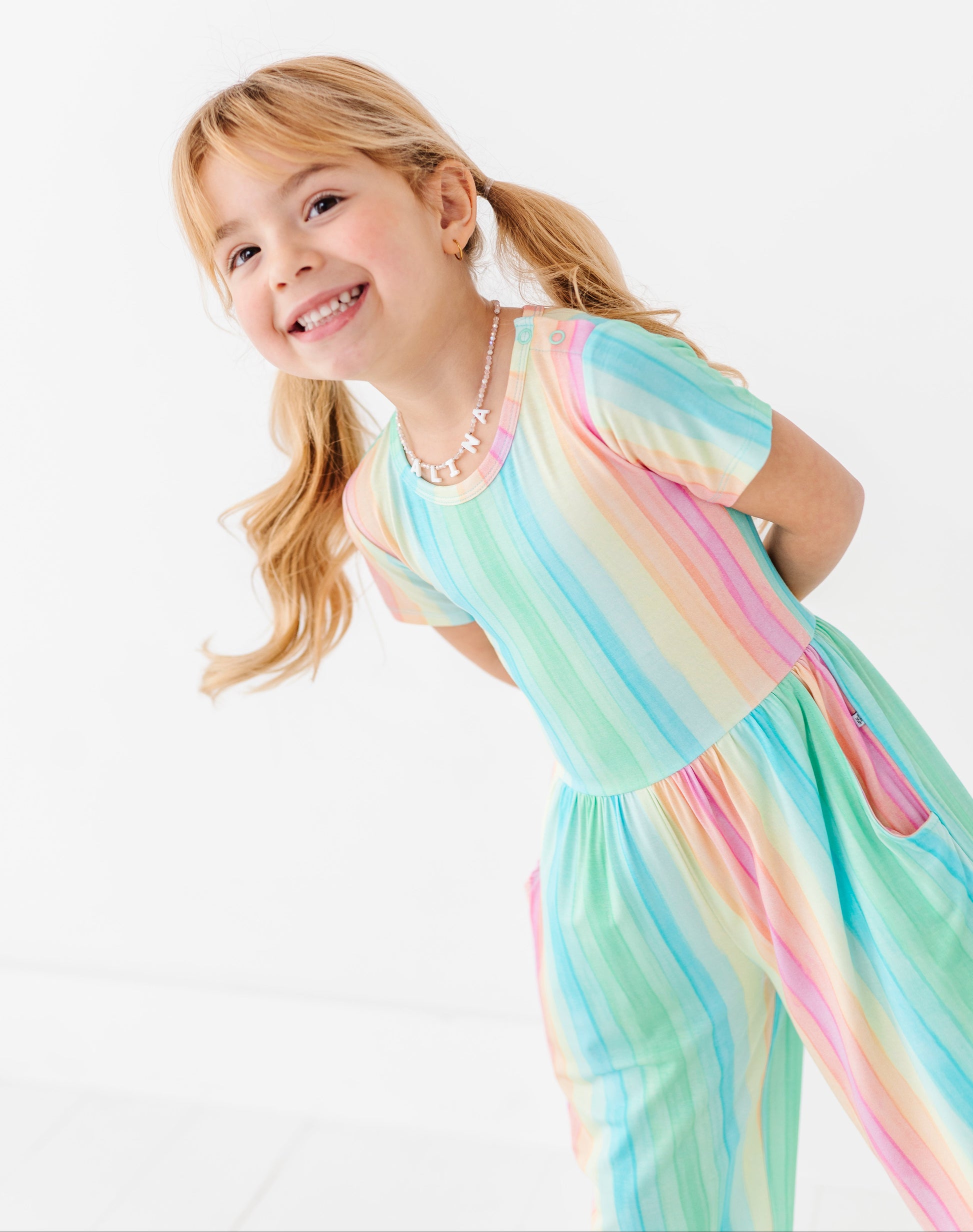 Kids rainbow stripe jumpsuit featuring short sleeves and flowy pant legs