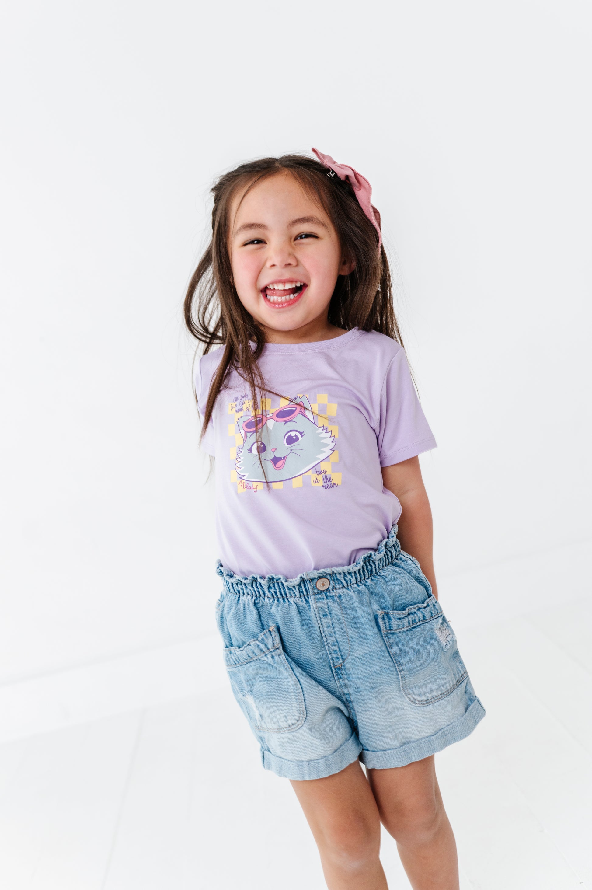 Child wearing a purple bamboo blend t-shirt with a 44 Cats design and denim shorts on a white background