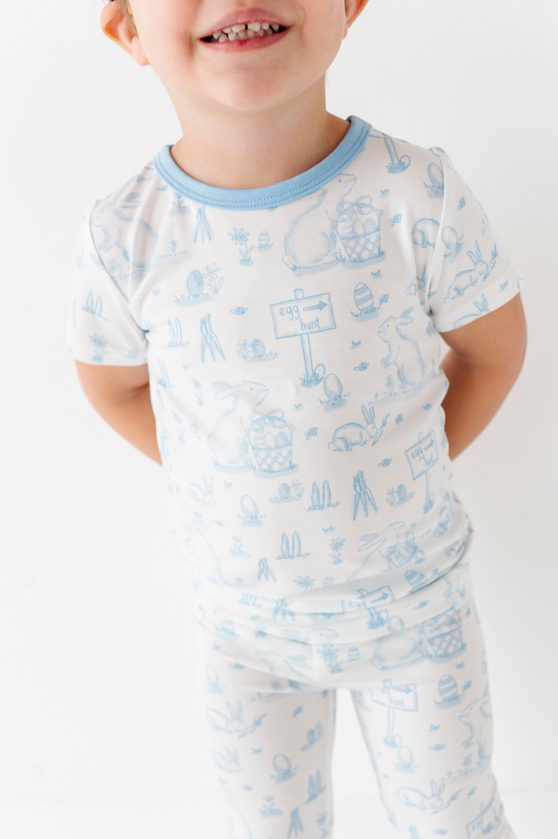 Child wearing a white bamboo Easter pajama set with blue patterns on a white background