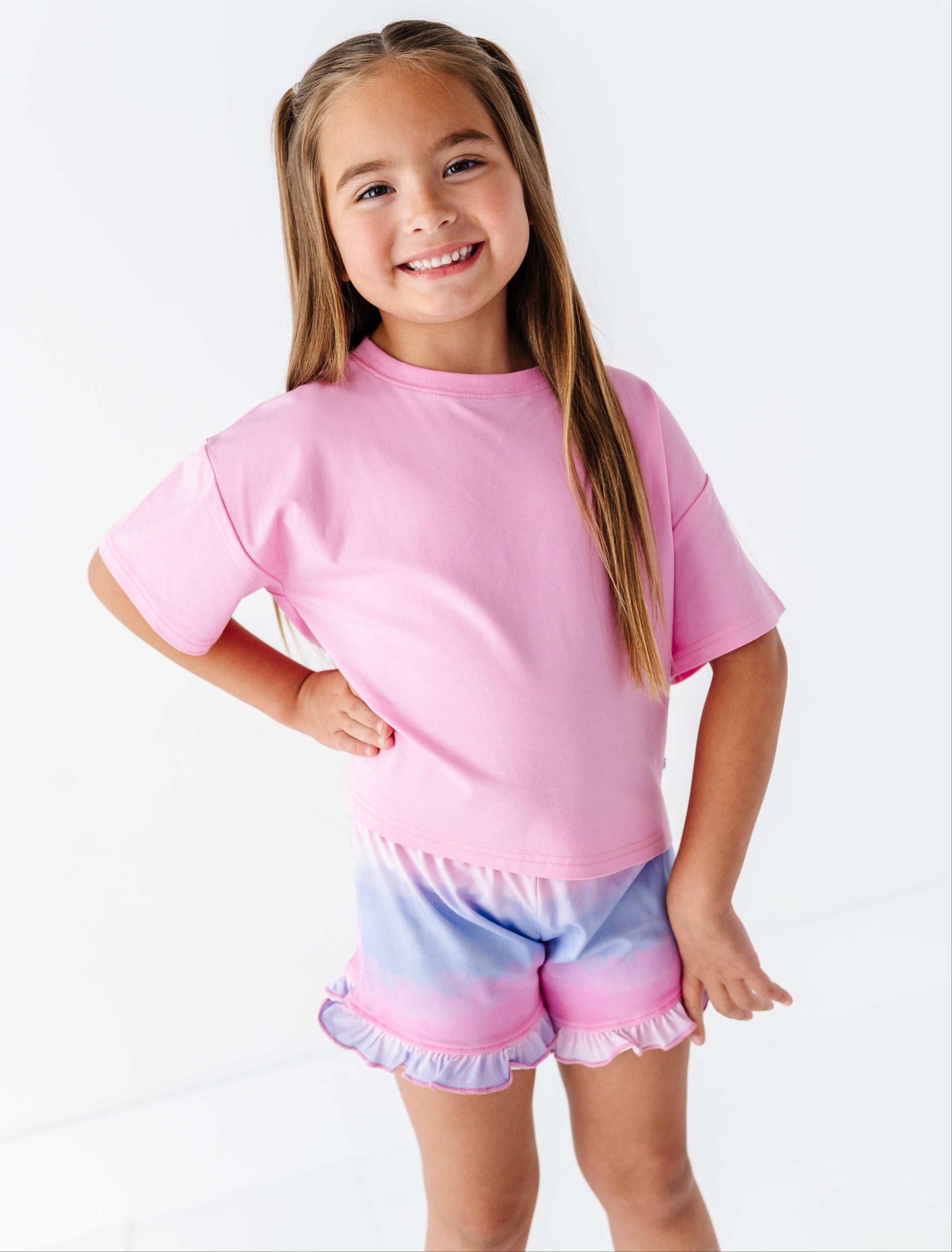 Young girl wearing a pink and purple tie-dye outfit on a white background