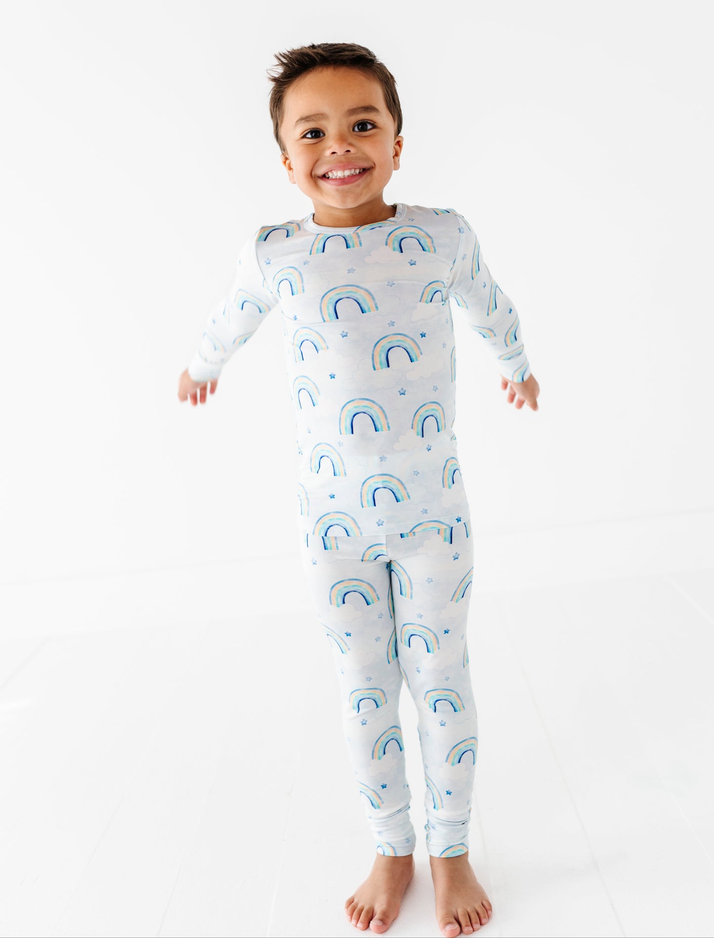 Child wearing a bamboo two-piece pajama set with watercolor rainbow pattern on a white background