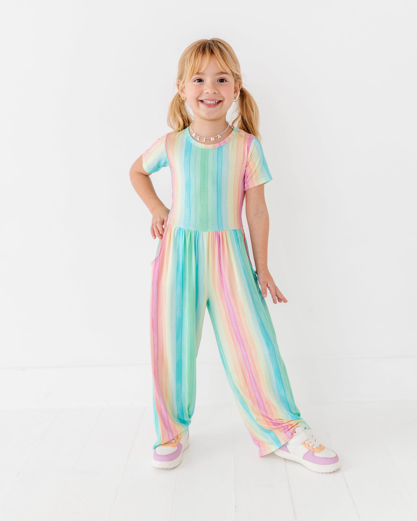 Child wearing pastel rainbow stripe jumpsuit perfect for everyday play and special moments