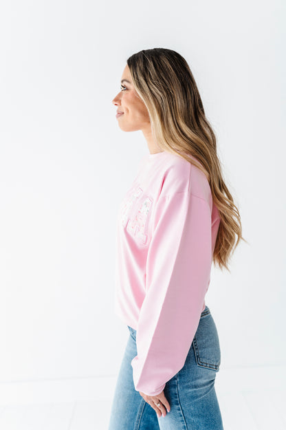 Woman wearing a pink crewneck and denim jeans on a white background
