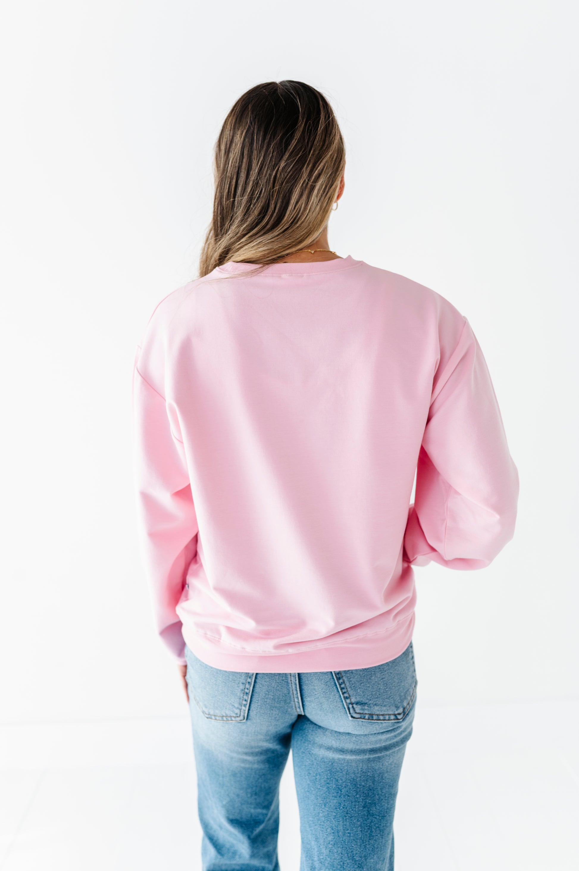 Woman wearing a pink bamboo sweatshirt and blue jeans on a white background