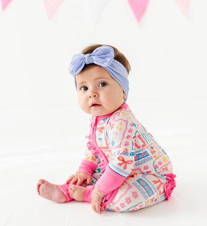 Baby wearing a colorful bamboo romper and headband on a white background