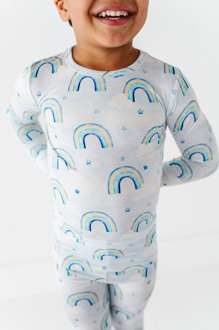 Child wearing a bamboo two-piece pajama set with watercolor rainbow pattern on a white background