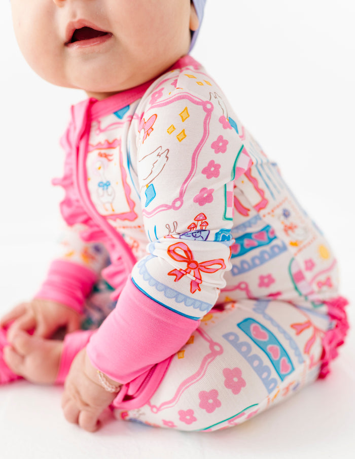 Baby wearing a colorful geese outfit with pink and white sleeves and pants on a white background
