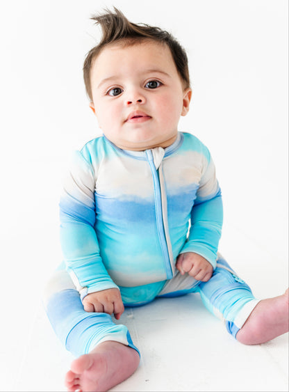 Baby wearing a blue and white gradient bamboo sleeper on a white background