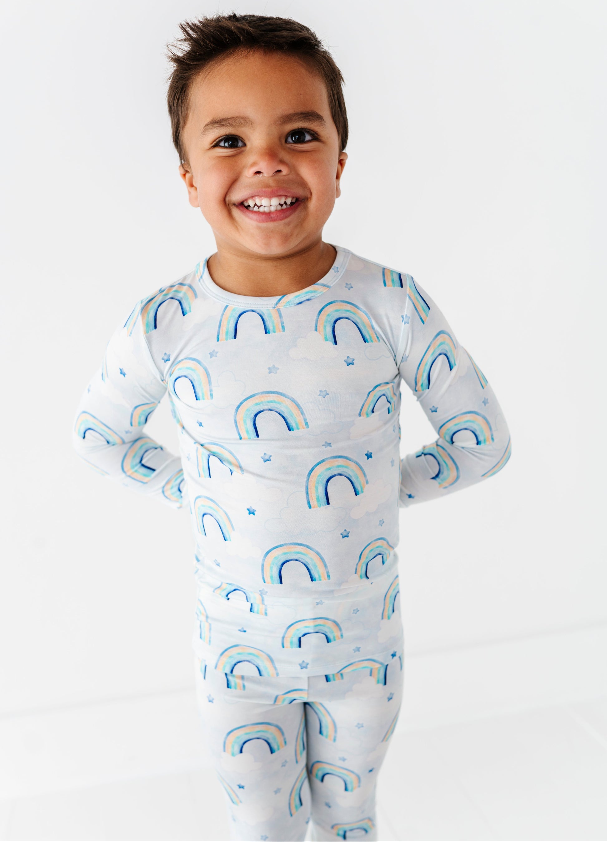 Child wearing a bamboo two-piece pajama set with watercolor rainbow patterns on a white background