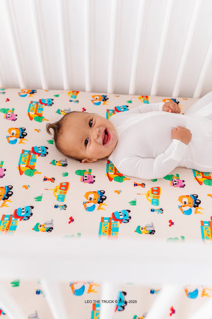 Baby lying on a colorful Leo the Truck bamboo crib sheet 