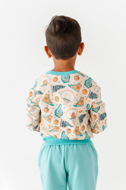 Child wearing a sports themed bamboo shirt and light blue pants on a white background