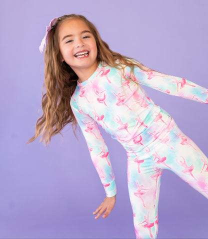 Young girl wearing a colorful ballet-themed pajama set against a purple background
