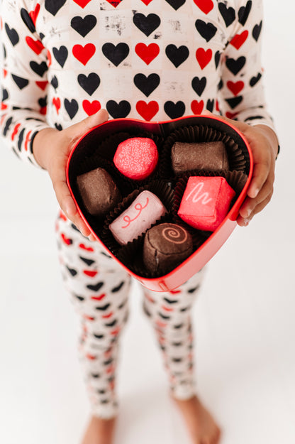 Toddler in King of Hearts two-piece pajamas holding heart-shaped chocolate box