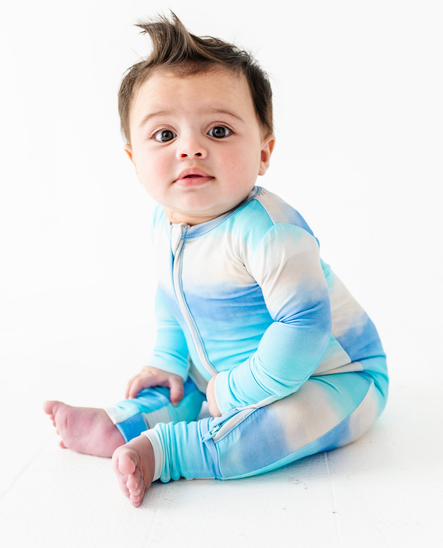 Baby wearing a blue and white ombre bamboo convertible romper on a white background
