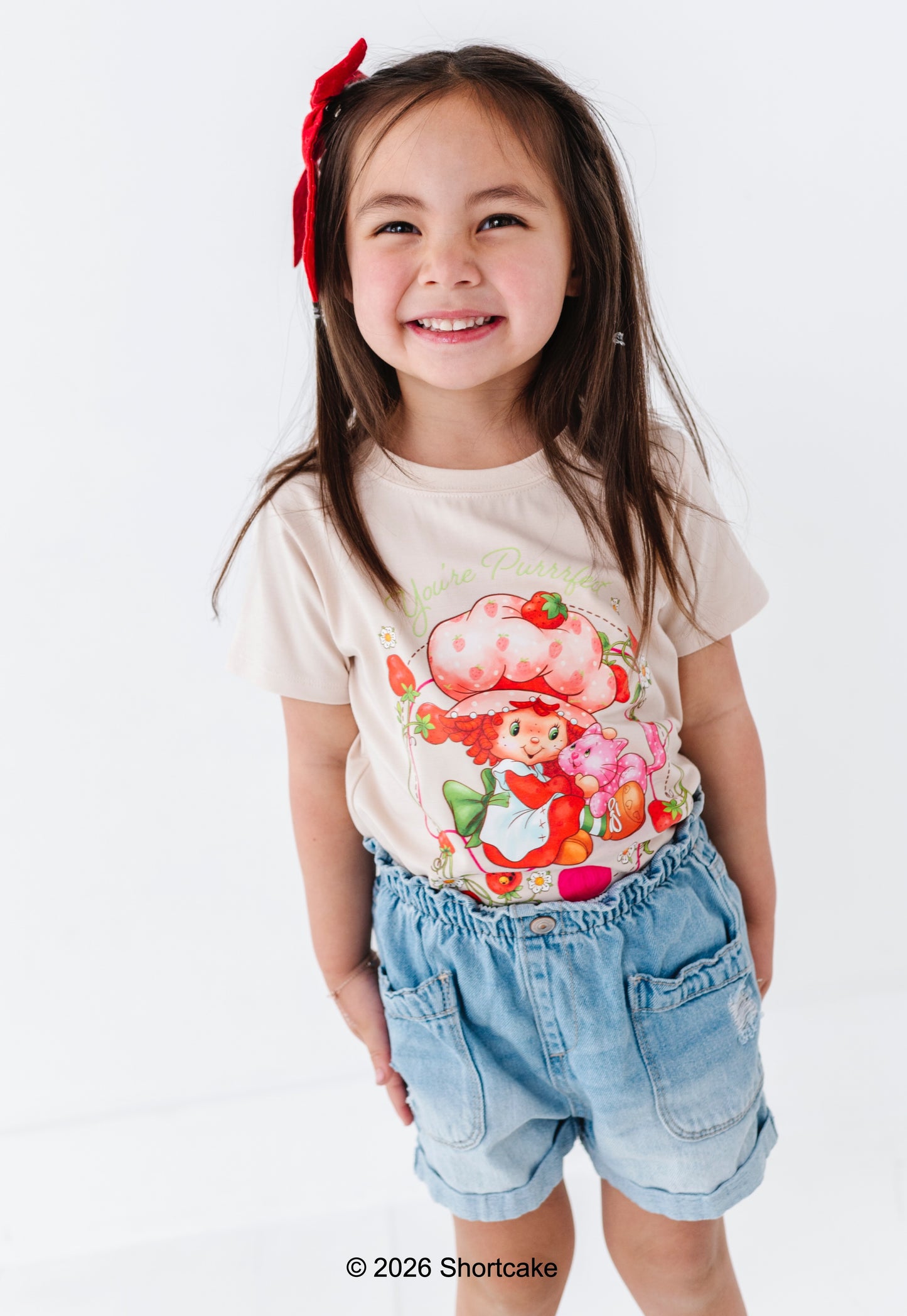 Young girl wearing an officially licensed Strawberry Shortcake™ t-shirt with denim shorts 