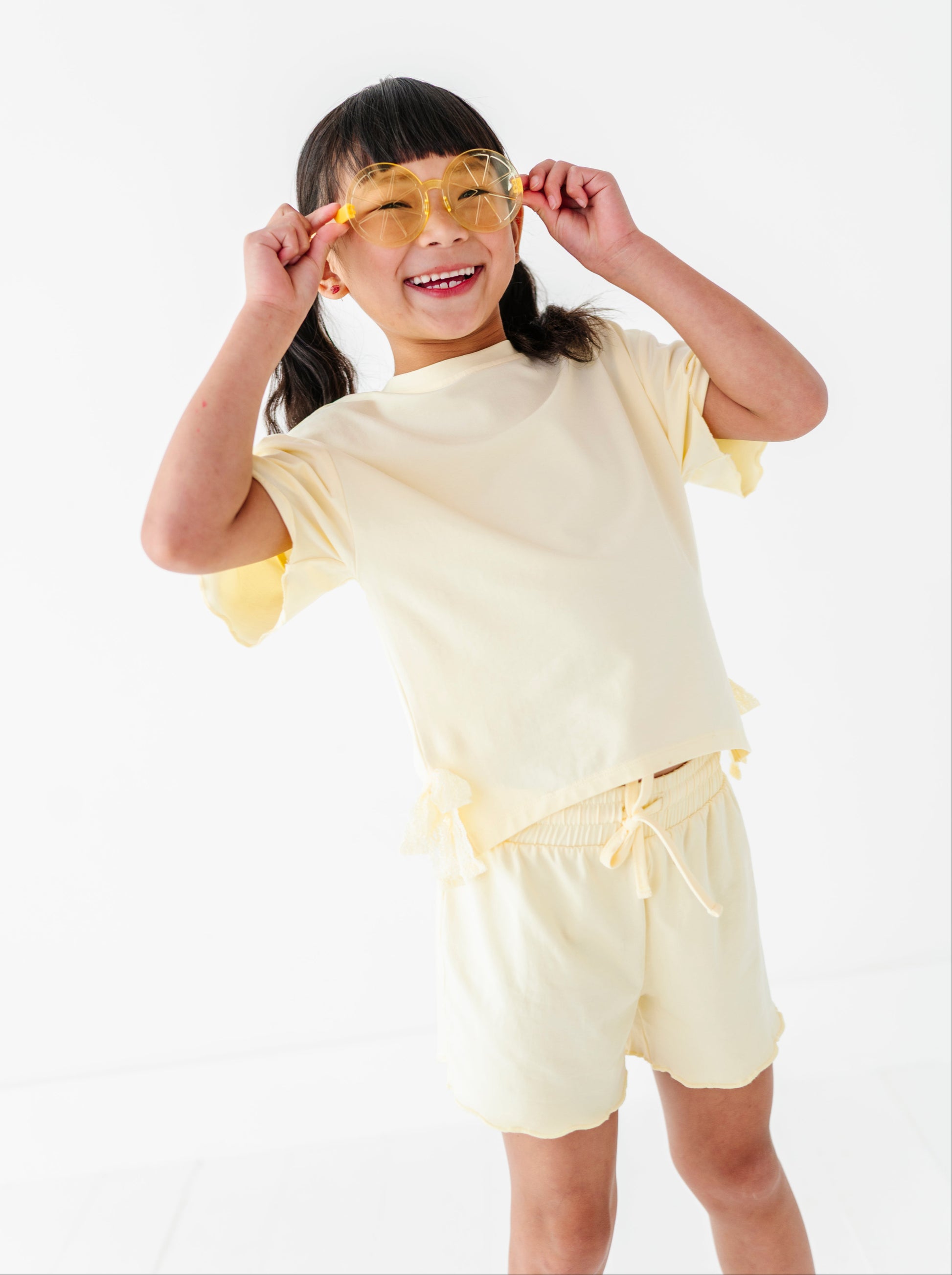 Child wearing a yellow outfit with sunglasses on a white background
