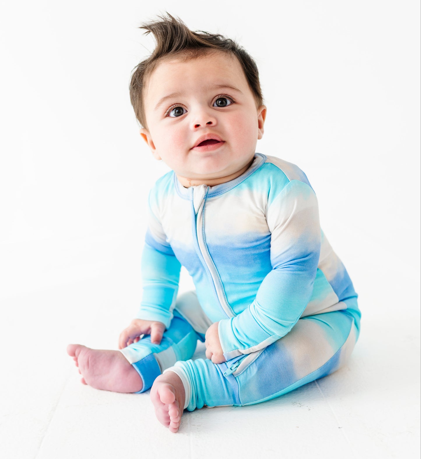 Baby wearing a blue and white gradient bamboo zip romper on a white background