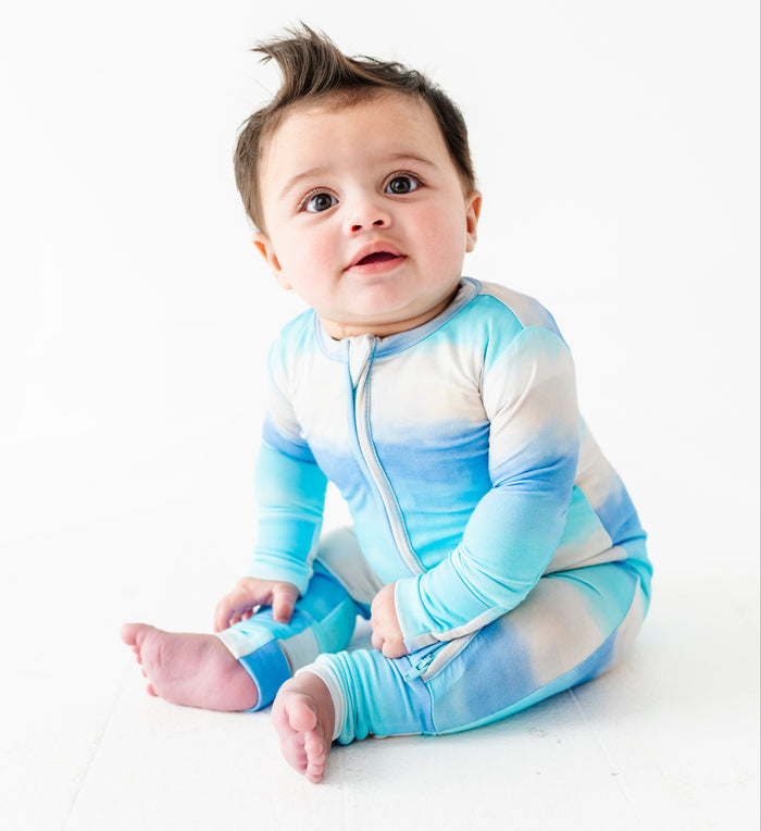 Baby wearing a blue and white gradient bamboo zip romper on a white background