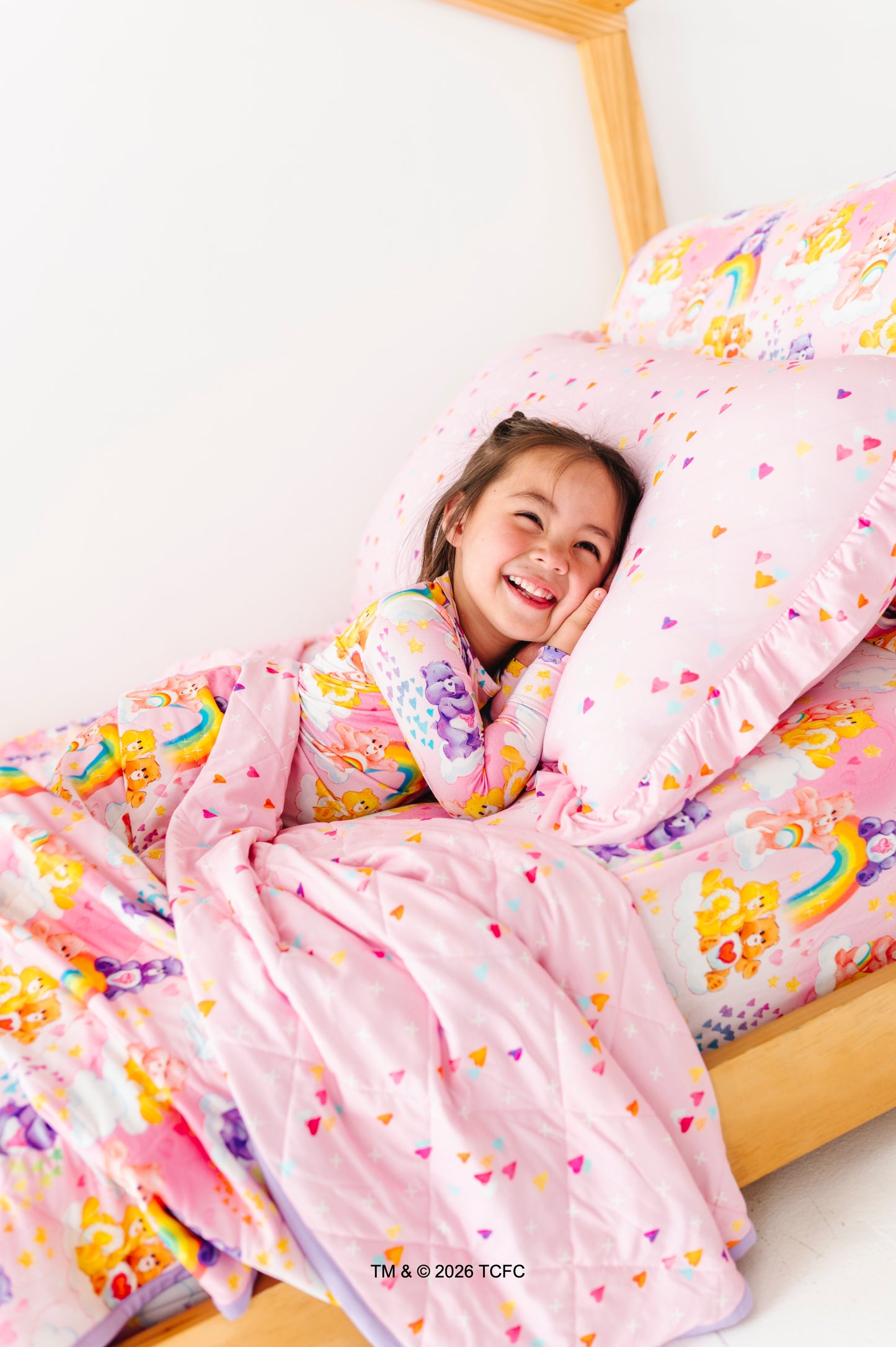 Child lying in bed with colorful bedding featuring cartoon characters