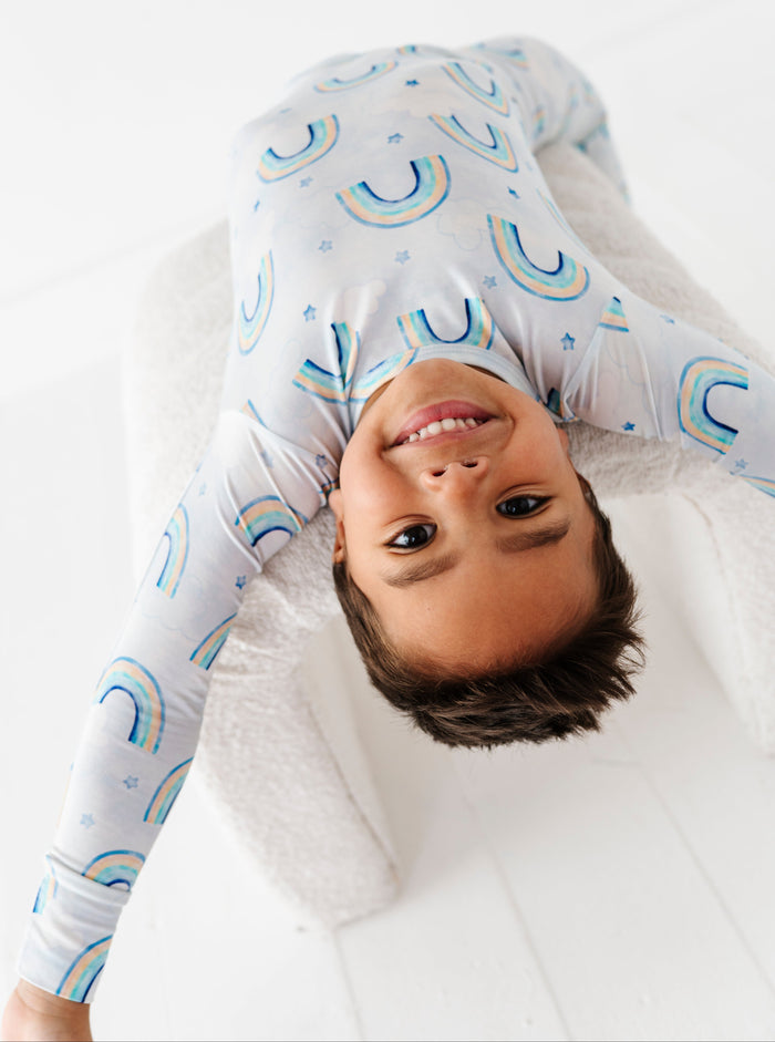 Child wearing a long-sleeve bamboo pj set with rainbow pattern on a white background