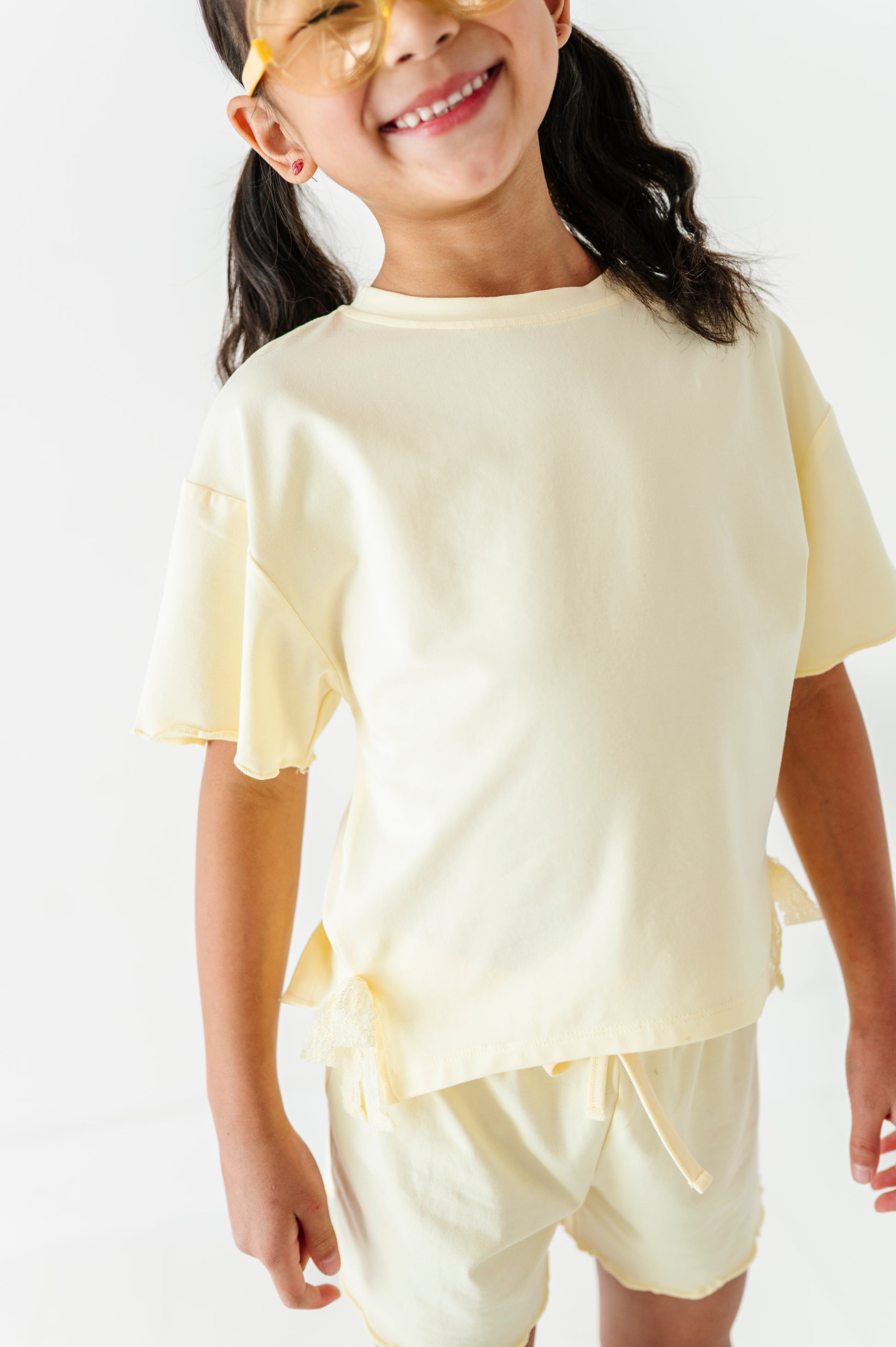 Young girl wearing a light yellow outfit with a plain background
