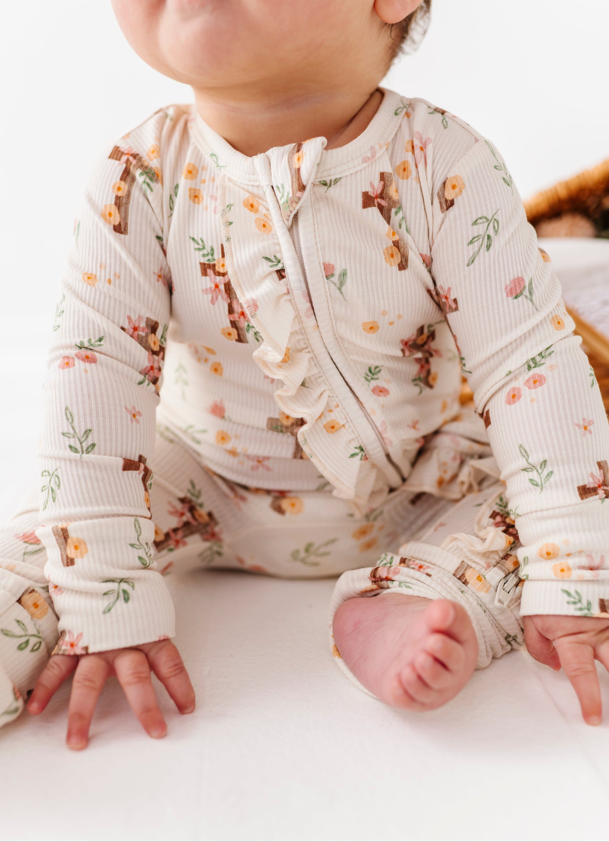 Baby wearing a floral bamboo pajama romper on a white background