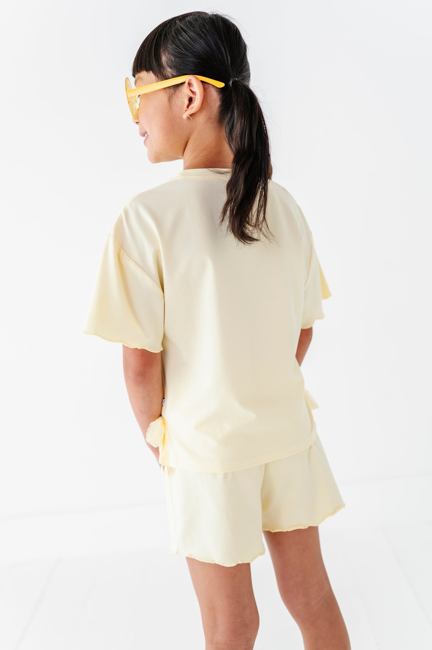 Girl wearing a light yellow outfit with a plain background