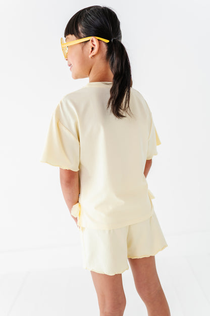 Girl wearing a light yellow outfit with a plain background