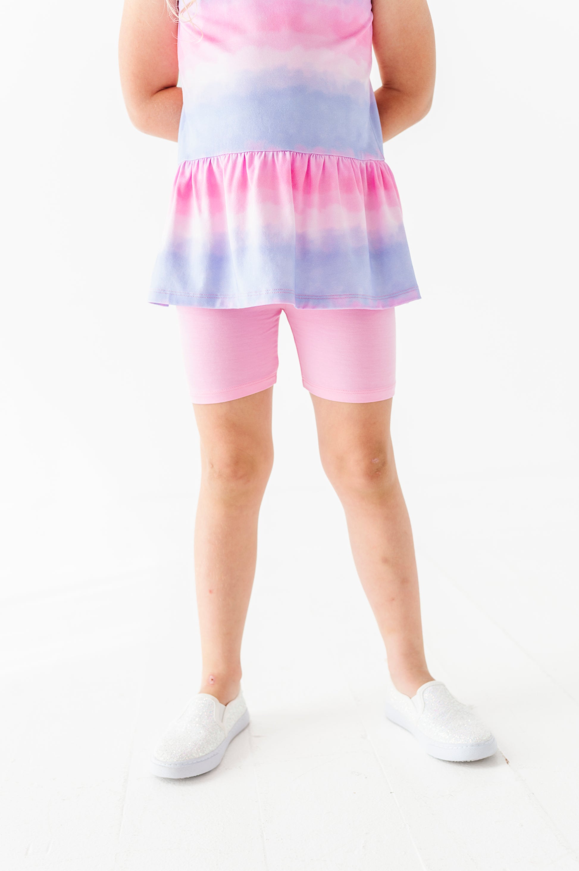 Person wearing a colorful tie-dye peplum top and bamboo biker shorts on a white background