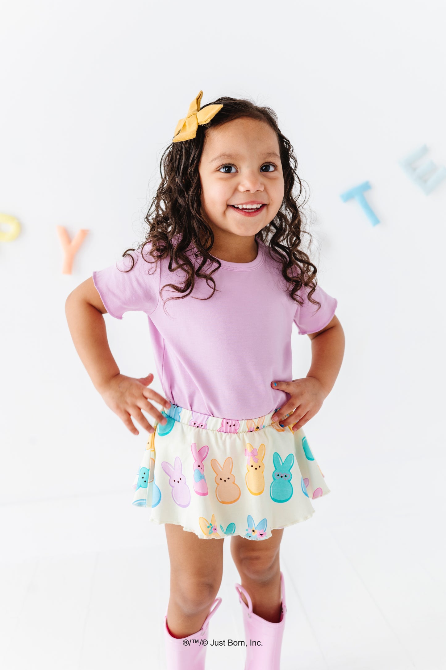 Young girl wearing a lavender shirt and colorful PEEPS® skirt on a white background