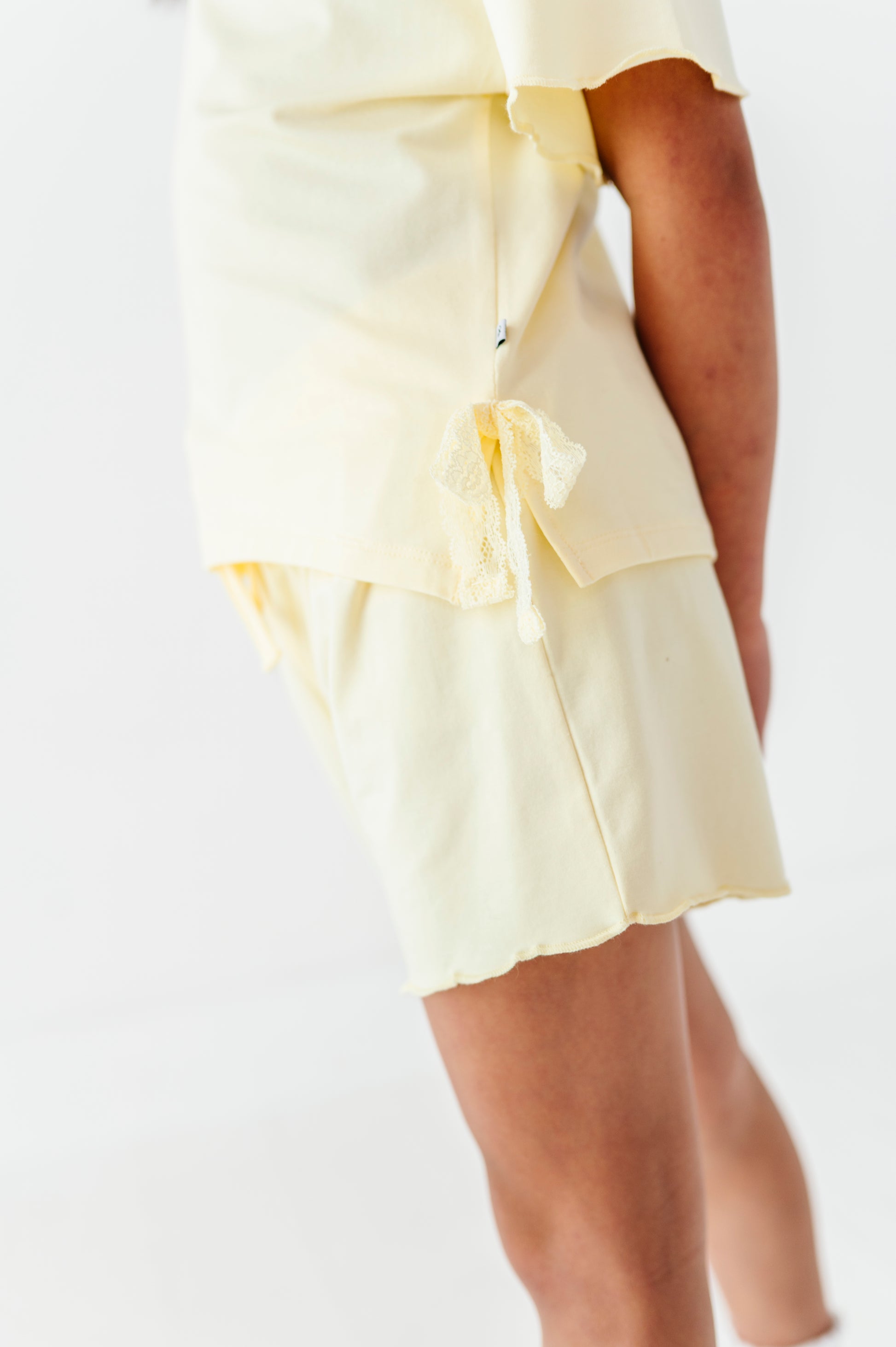 Light yellow outfit  with ruffled details on a white background