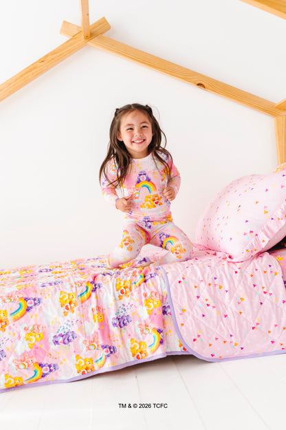 Child in Care Bears™ pajamas bouncing on a bed featuring Care Bears™ bedding 
