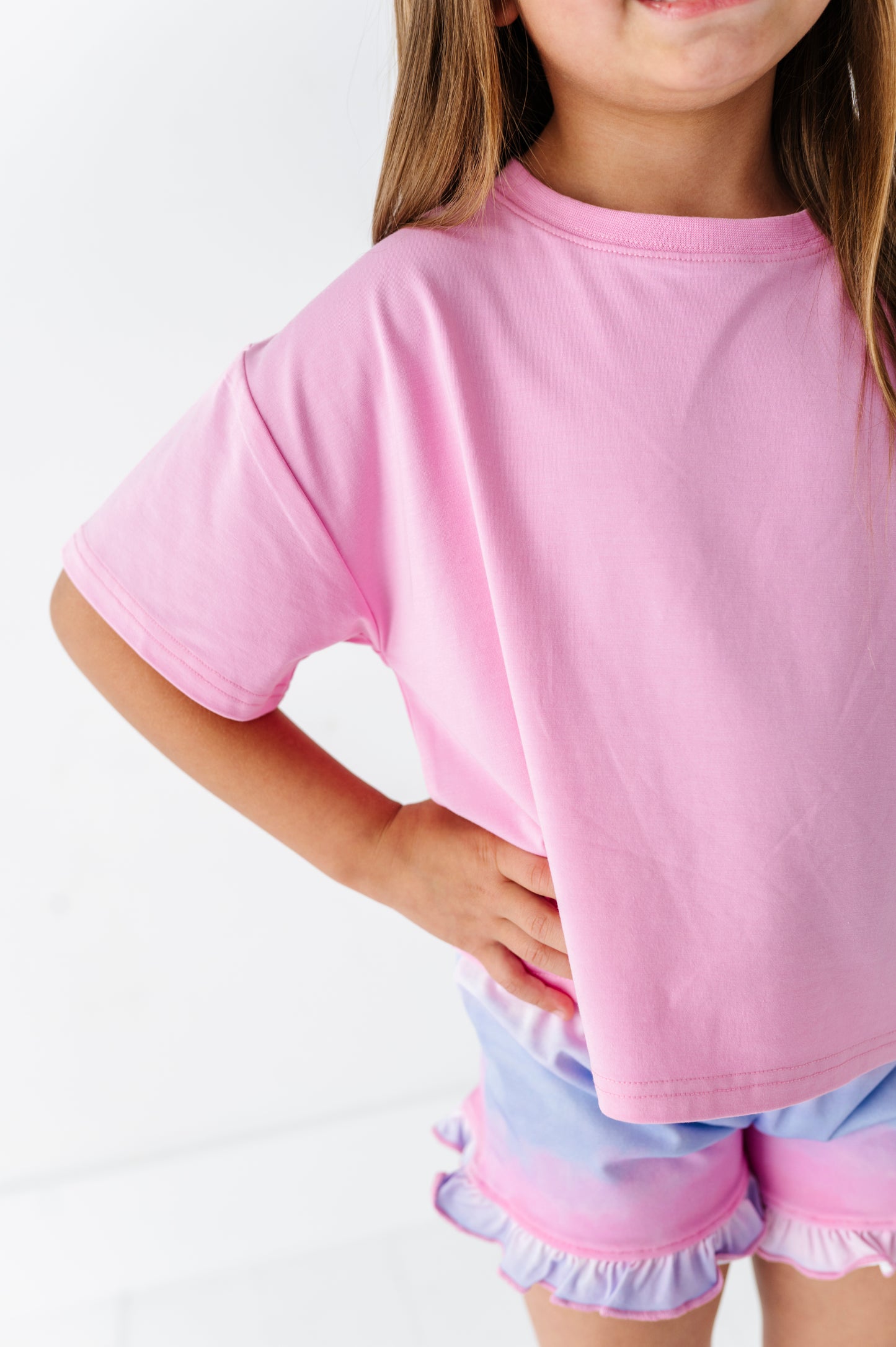 Child wearing a pink bamboo-cotton boxy shirt and light purple bamboo shorts on a white background