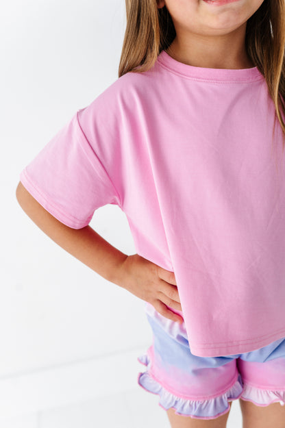 Child wearing a pink bamboo-cotton boxy shirt and light purple bamboo shorts on a white background