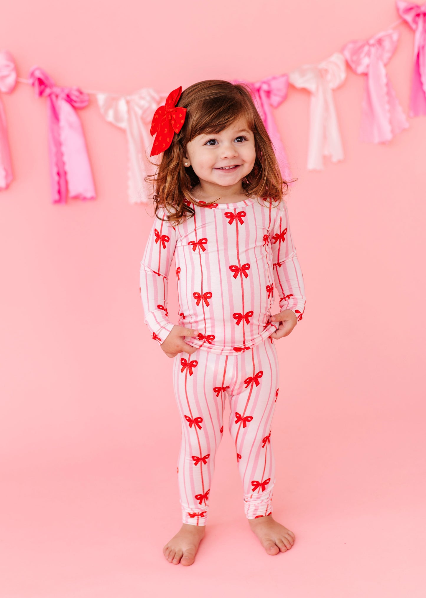 Child in Ruby Ribbons bamboo pajamas with red bows and pink stripes