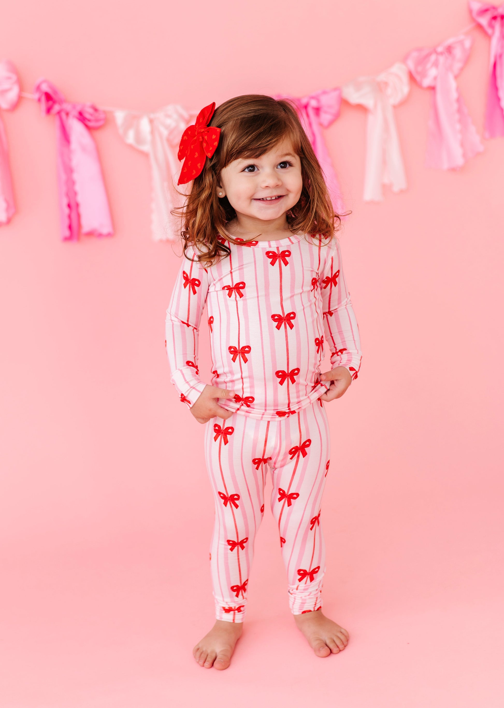 Child in Ruby Ribbons bamboo pajamas with red bows and pink stripes