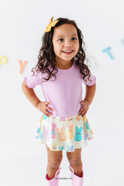 Young girl wearing a pink top and colorful skirt with PEEPS®  design on a white background.