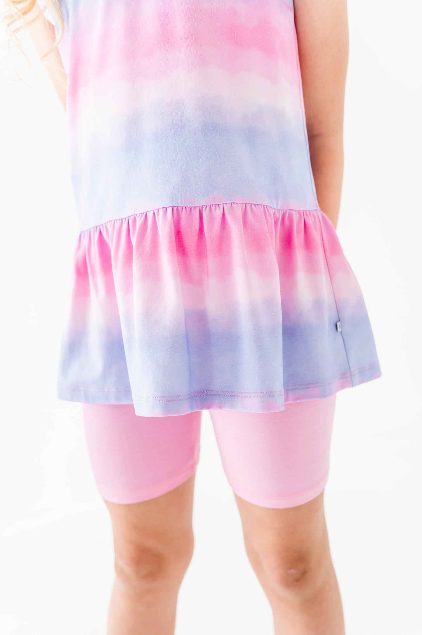 Pastel tie-dye bamboo-cotton peplum top with pink bamboo biker shorts on a white background