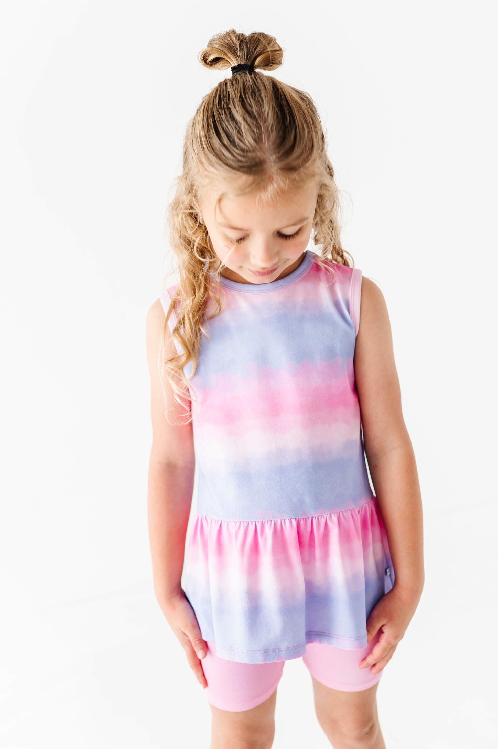 Young girl wearing a tie-dye bamboo top with pink and purple hues on a white background