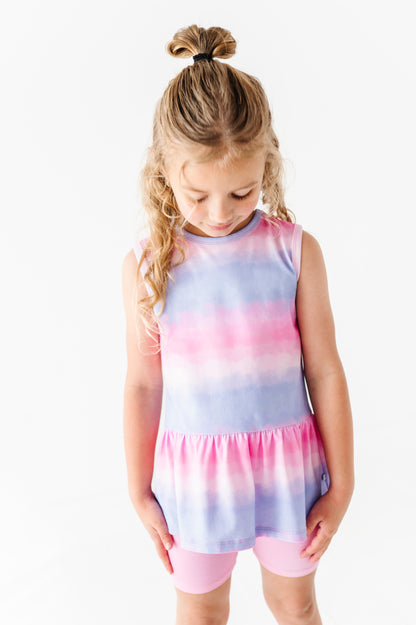 Young girl wearing a tie-dye bamboo top with pink and purple hues on a white background