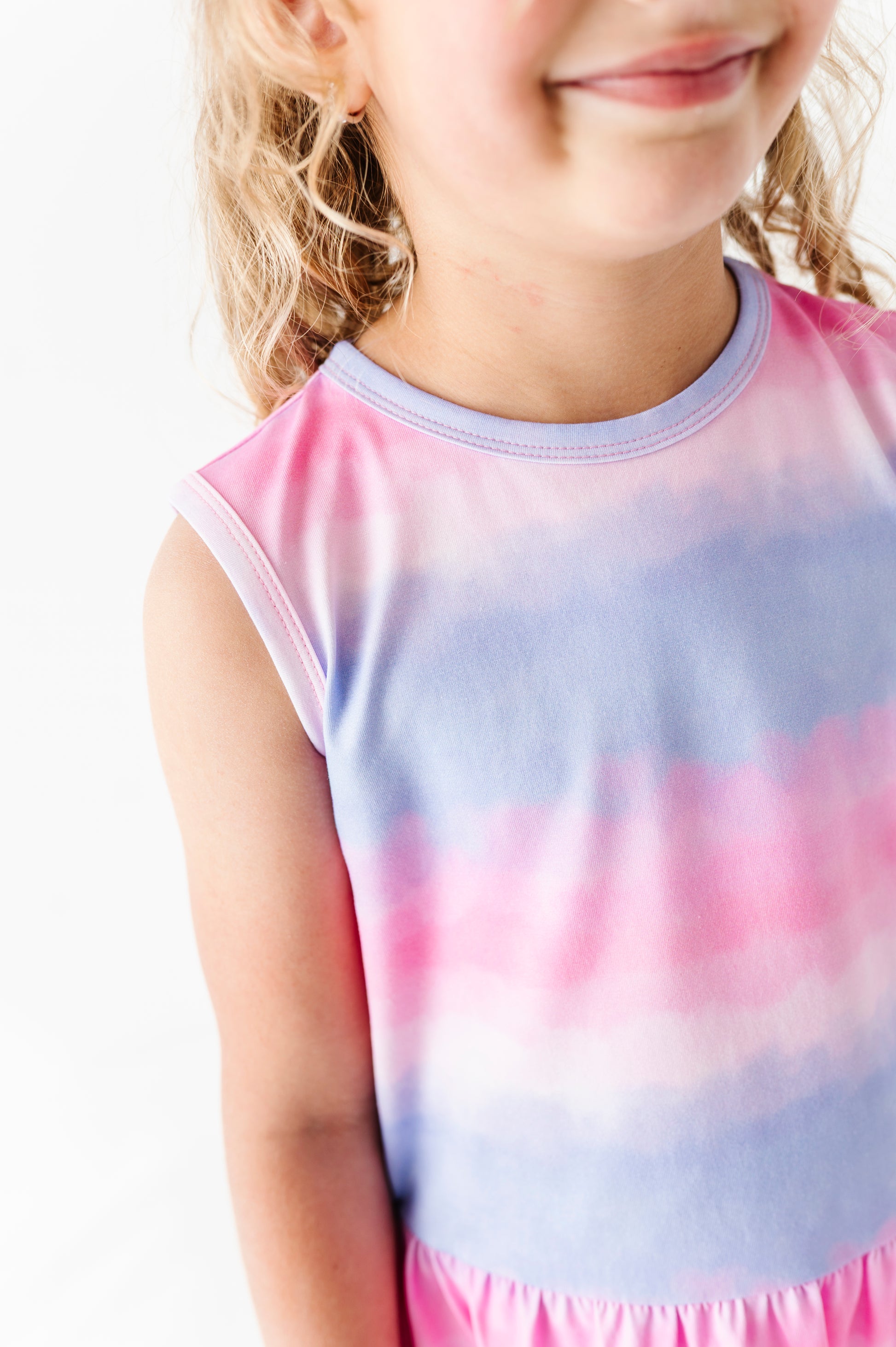 Child wearing a tie-dye bamboo-cotton peplum top with pink and blue gradient on a white background