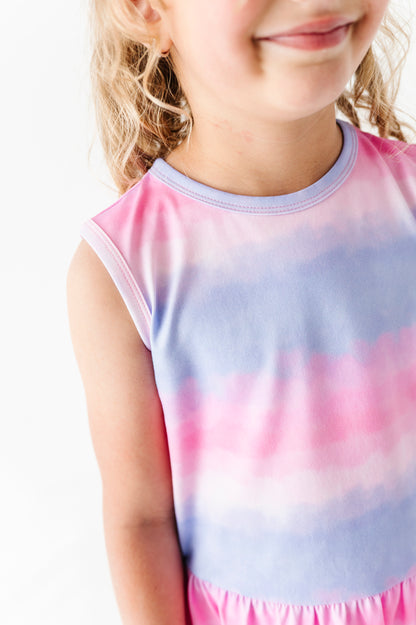 Child wearing a tie-dye bamboo-cotton peplum top with pink and blue gradient on a white background
