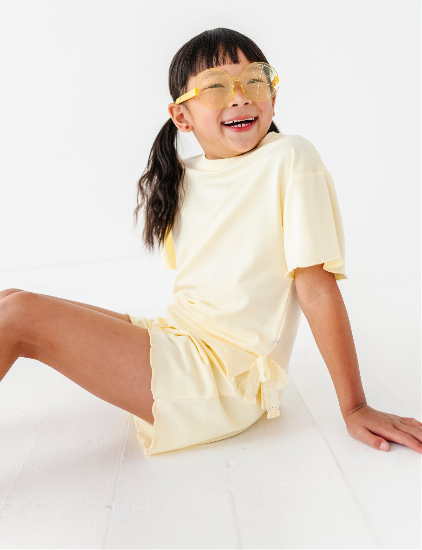 Child wearing a yellow outfit and sunglasses on a white background
