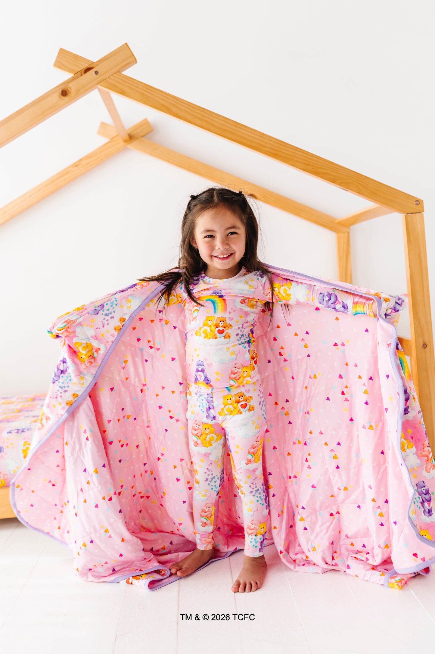 Little girl wearing Care Bears™ bamboo pajamas holding a Care Bears™ bamboo quilted blanket