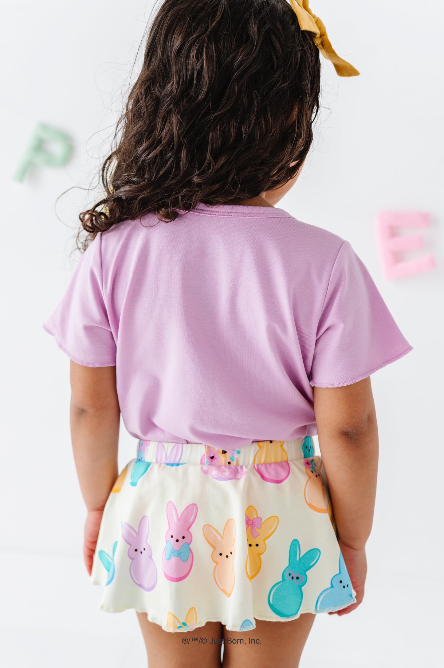 Child wearing a lavender shirt and a PEEPS® skirt on a white background.