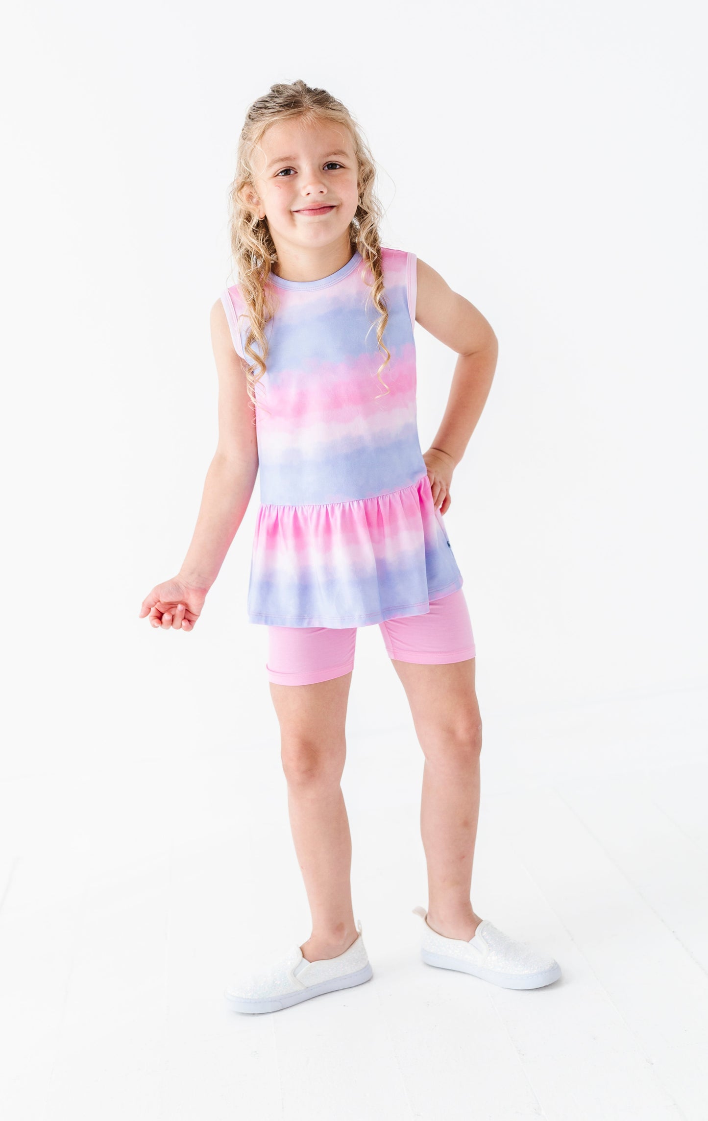 Young girl wearing a tie-dye bamboo-cotton peplum top and shorts set on a white background