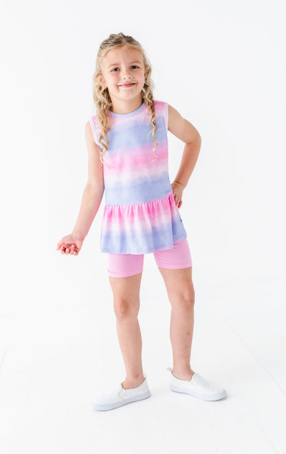 Young girl wearing a tie-dye bamboo-cotton peplum top and shorts set on a white background