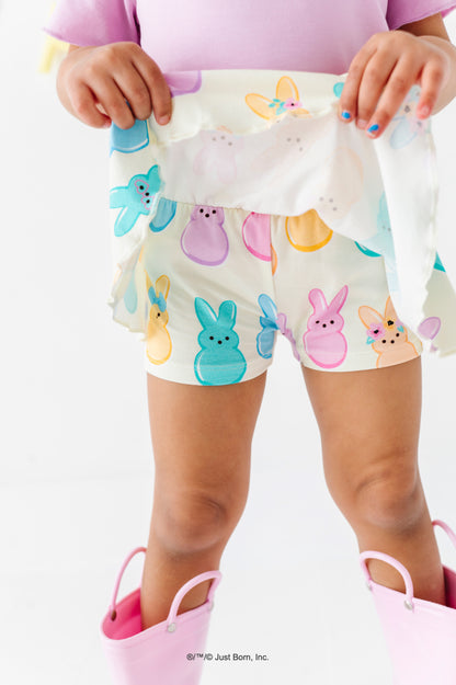 Child wearing a colorful PEEPS®-themed skirt with pink rain boots on a white background